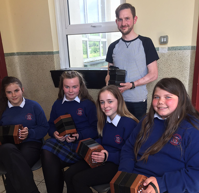 Music teacher Pádraig Rynn from Music Generation, with first year students (seated) Méadhbh Duibhne Ní Chochláin, Leighara Scarlóg, Joanie Ní Slatara, and Sadhbh Ní Fhinn